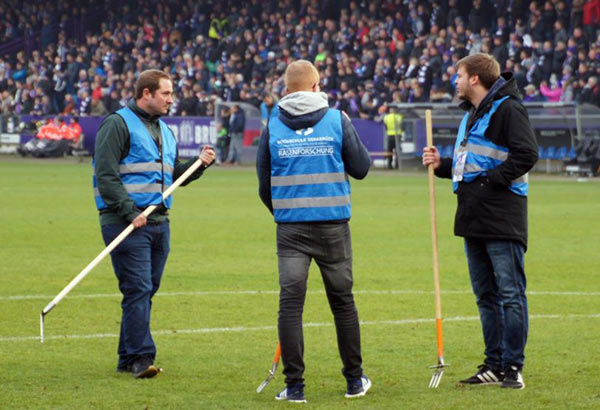 Praktische Rasenforschung mit der Pitchgabel auf dem Stadionrasen.